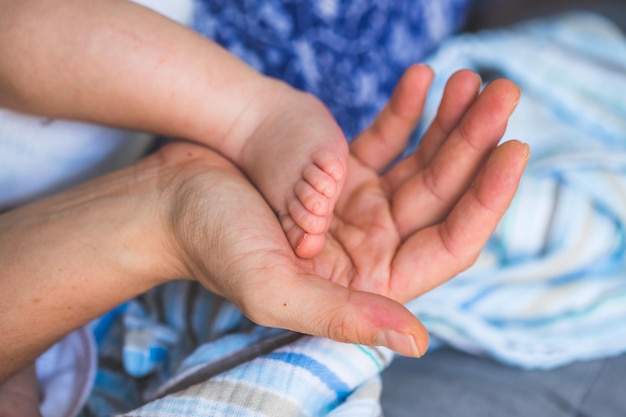 赤ちゃんと新生児の概念 生まれたばかりの赤ちゃんの足を保持している母親の手