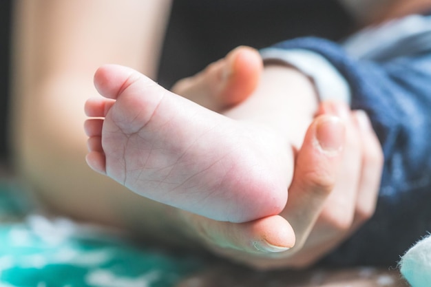 赤ちゃんと新生児の概念 生まれたばかりの赤ちゃんの足を保持している母親の手