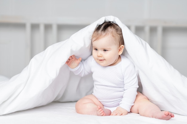 Baby onder de deken op het bed thuis, het concept van familie en kinderen