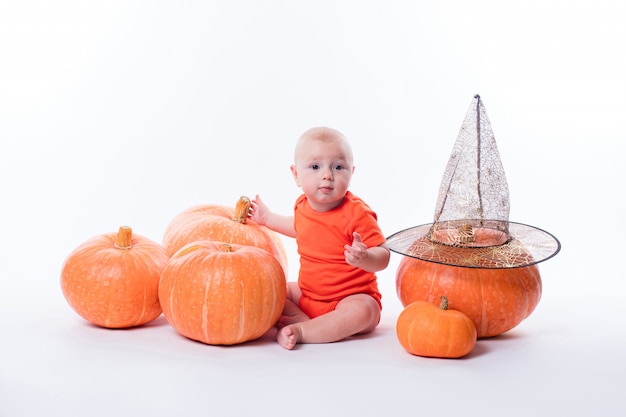 Baby in orange tshirt sitting on a white wall surrounded