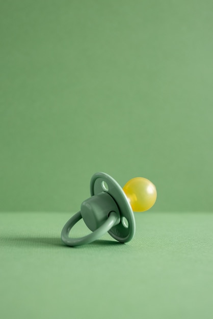 Baby pacifier on a green background, place for an inscription side view