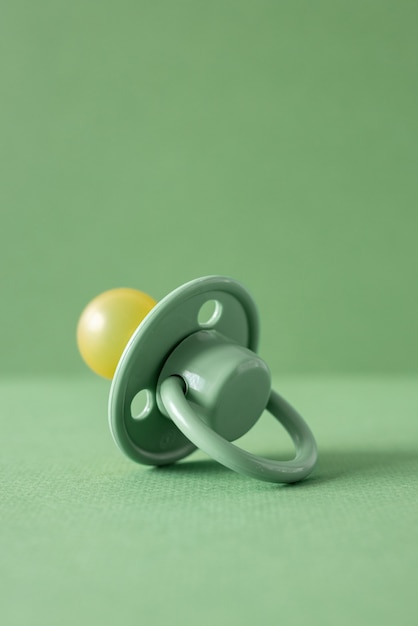 Baby pacifier on a green background, place for an inscription side view