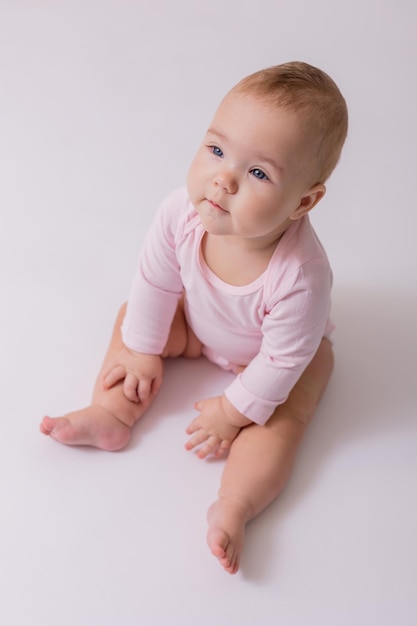 ピンクのボディースーツを着た赤ちゃんが床に座っているテキスト用のトップビュースペース高品質の写真