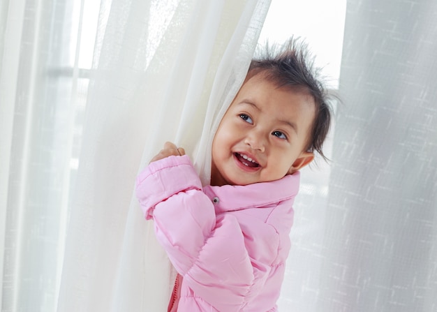 baby playing hide and seek behind the curtain