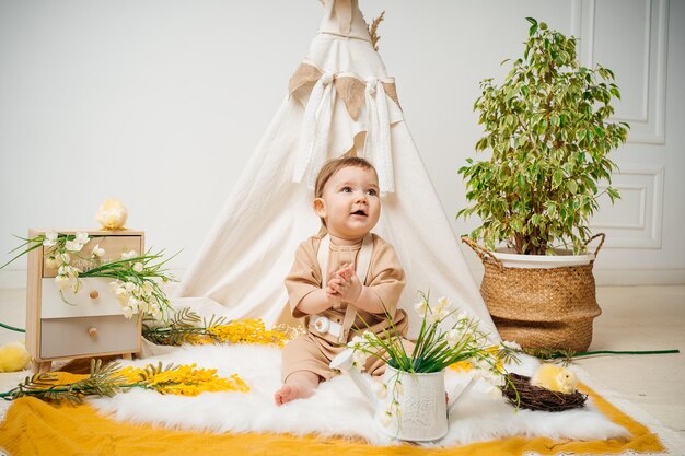 Photo baby playing at home on the floor tent and flowers spring