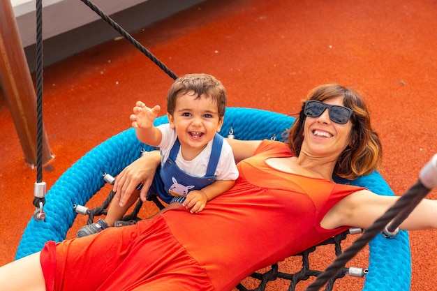 Baby playing in a playground having fun in summer having fun with his mother