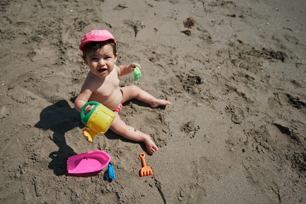 A baby playing with beach toys in the sand