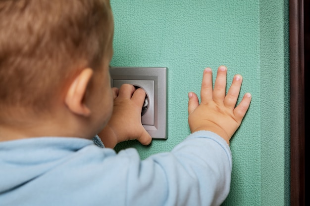 Baby playing with electrical outlet on floor at home.