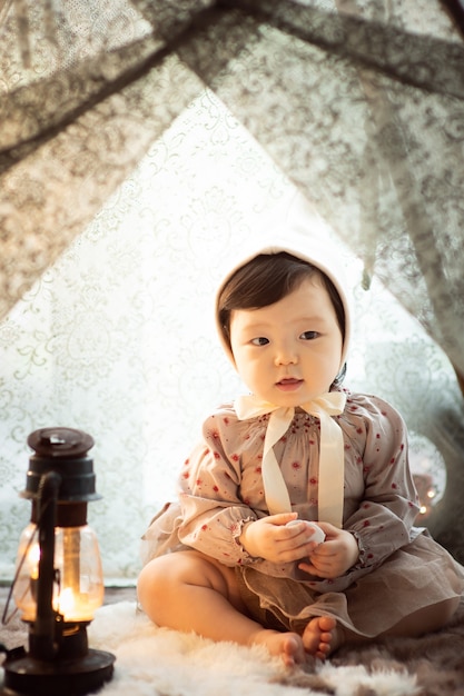 A baby playing with a light in a tent