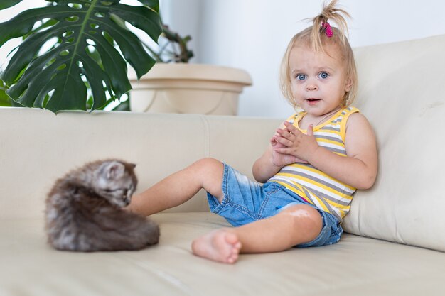 ソファで小さな子猫と遊ぶ赤ちゃん