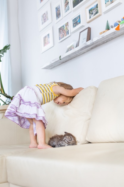 Baby playing with a little kitten on the couch