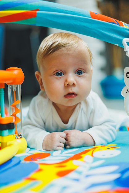 赤ちゃんは2ヶ月間発達マットで遊んでいます小さな子供のためのおもちゃのカーペットです