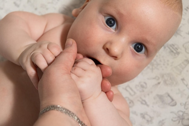 the baby plays and eats his hands and looks at the camera