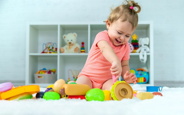 아기는 그녀의 방에서 장난감을 가지고 노는다 선택적 초점 아이