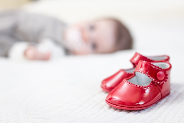 Baby red shoes and babe lying on the background