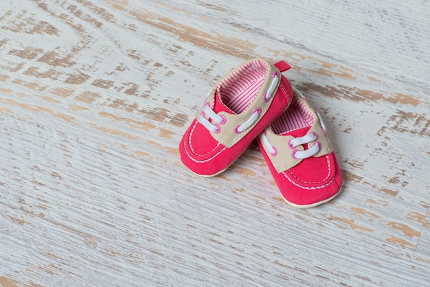 Baby red shoes on a rope against a white brick wall.