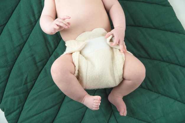 baby in reusable woolen diapers on a green mat