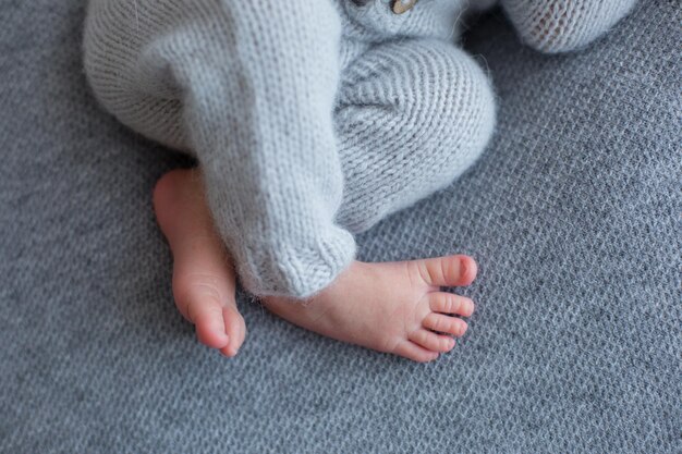 A baby's bare foot sits on a grey carpet.