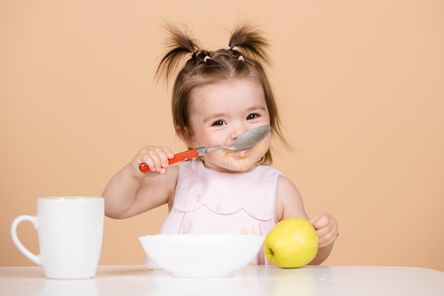 Baby's die gezond eten voor een baby Baby's eerste maaltijd Het kind eet alleen met een lepel en bord