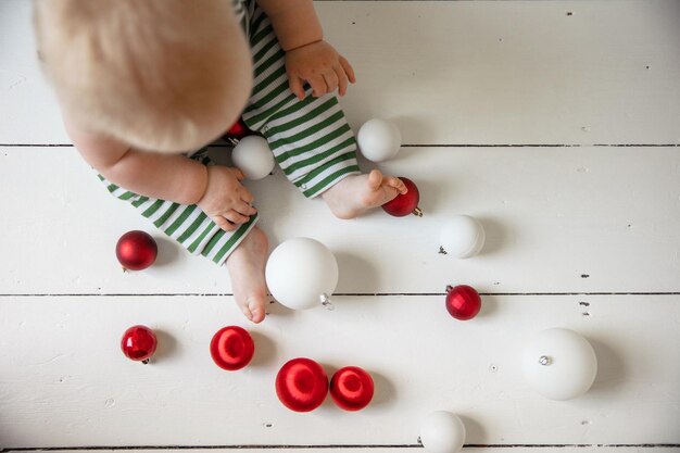 Baby's eerste kerstbaby zat op de vloer te spelen met kerstversieringen