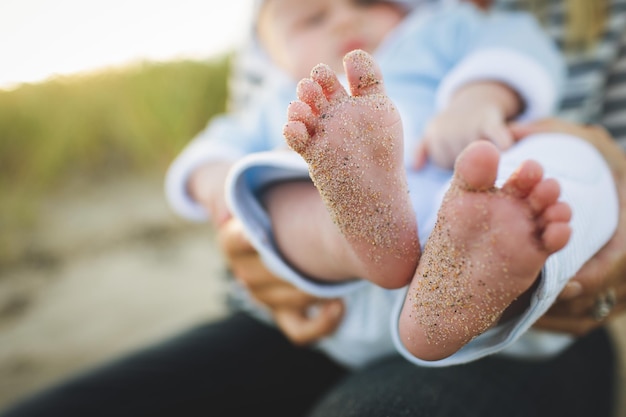 A baby's feet are covered in sand.