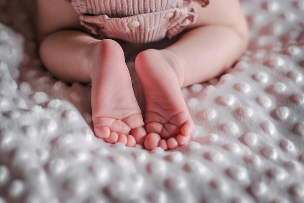 Baby's feet. Bare feet of a cute newborn baby girl. Cozy morning bedtime at home.