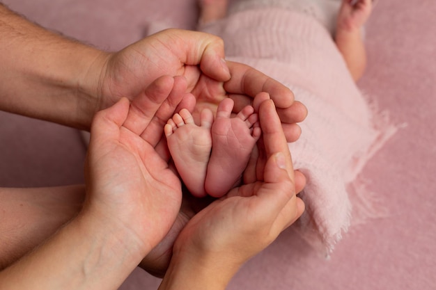 Baby\'s feet in the hands of the older child and mom