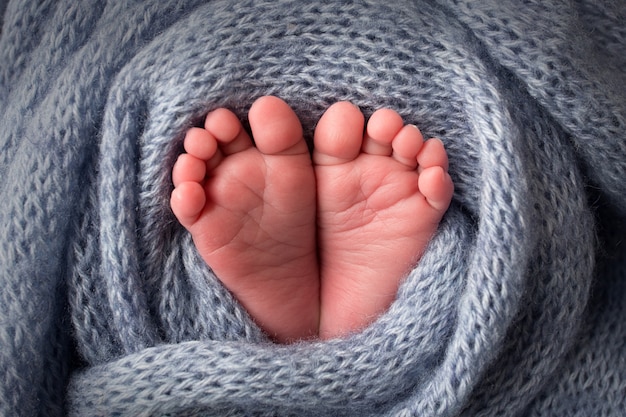 부드러운 하늘색 모직 담요에 아기의 발. 작은 발가락. 아기의 발가락에 니트 심장. 흑백 사진입니다. 고품질 사진
