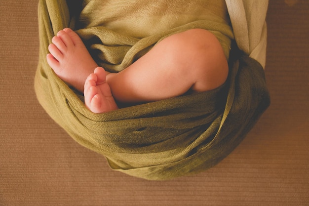 a baby's feet wrapped in a green blanket is wrapped in a green towel.