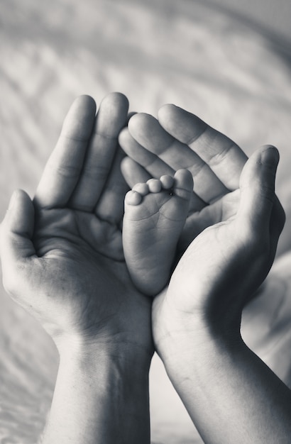 Photo a baby's foot in his mother's hands seen from above