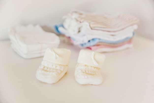 Baby's knitted sock in front of diaper and clothing stacked