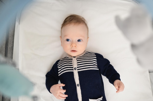 Photo baby's morning baby products concept baby boy 5 months old lying in a crib in the children's room