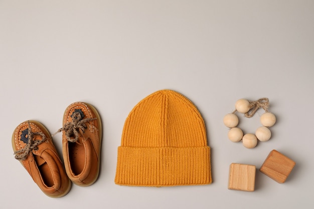 Baby shoes, hat and toys on light gray background.