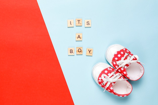 Baby shoes or toddler shoes with "It's a girl" or "It's a boy" lettering,top view.