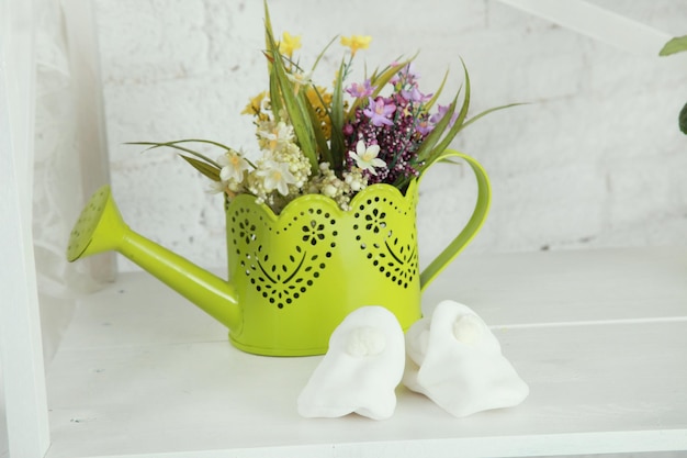 Photo baby shoes on the white wooden background with flowers in waterpot