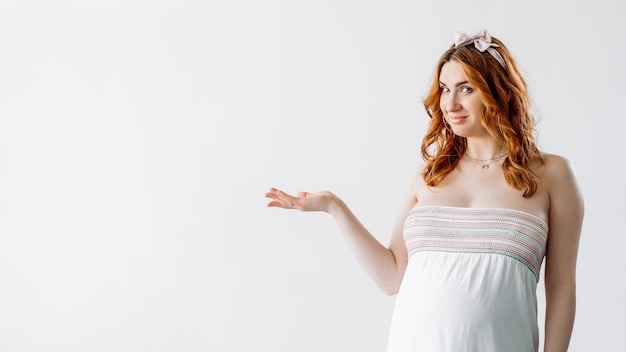 ベビーシャワーパーティー妊婦オープンパーム重要な情報広告の背景かわいい笑顔のおなか女性が手で隔離された白いコピースペースを促進する