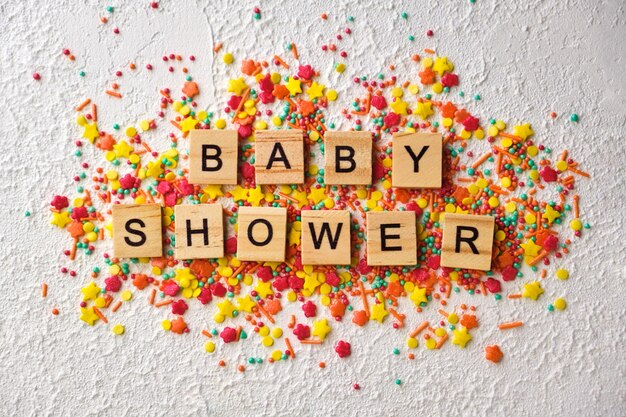 Baby shower wooden words on colorful confetti, on white textured background