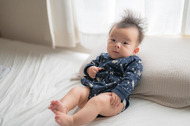 A baby sits on a bed with a pillow that says'i'm a baby '