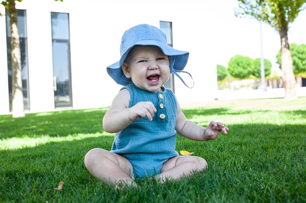 Baby sits on the grass in the park and laughsSummer