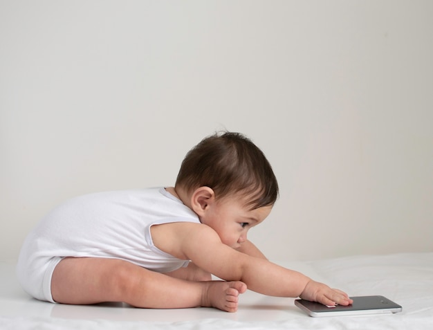 Baby sits and try to reach to the phone 