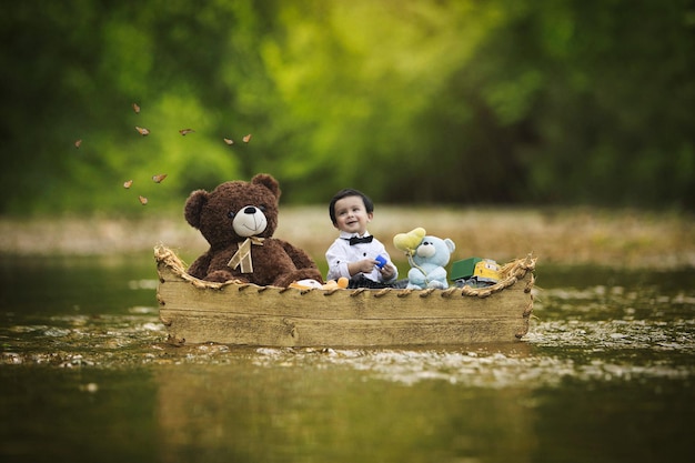 Baby sitting in boat floating in water with teddy and toys all around