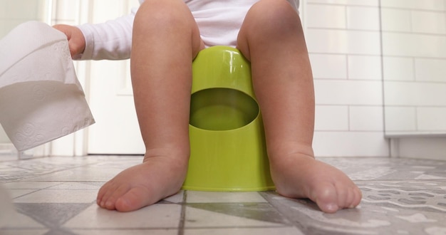 Baby sitting chamberpot his legs hanging down pot