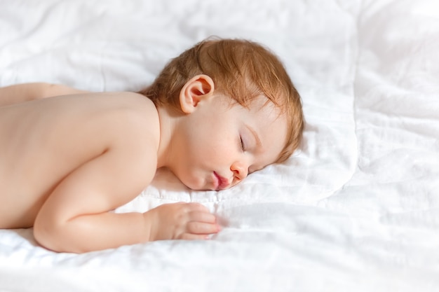 Baby slaapt op een witte sprei, schoon en minimalistisch.