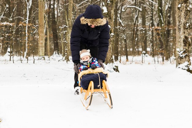 Baby sledding sulla neve nella foresta