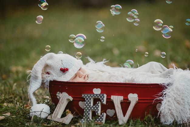 Photo baby sleeping in a basket on the lawn with soap bubbles