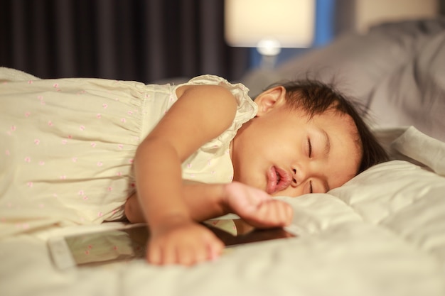 baby sleeping on bed after playing tablet