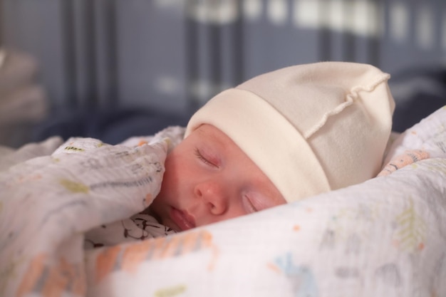 Baby sleeping on white sheets in bed with a blanket