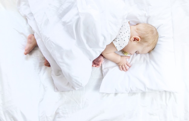 Baby sleeps on a white bed