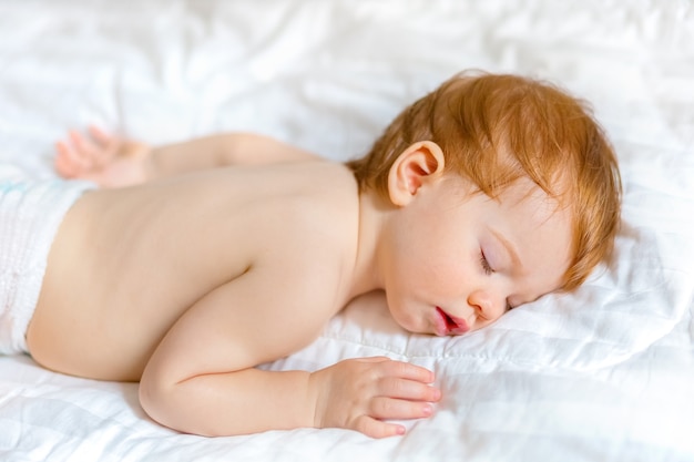 Il bambino dorme su un copriletto bianco, pulito e minimalista.