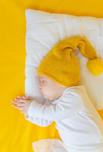 Il bambino dorme con il cappello su uno sfondo giallo, inverno e concetto di vacanza